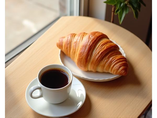 Croissant et tasse de café expresso fumant.